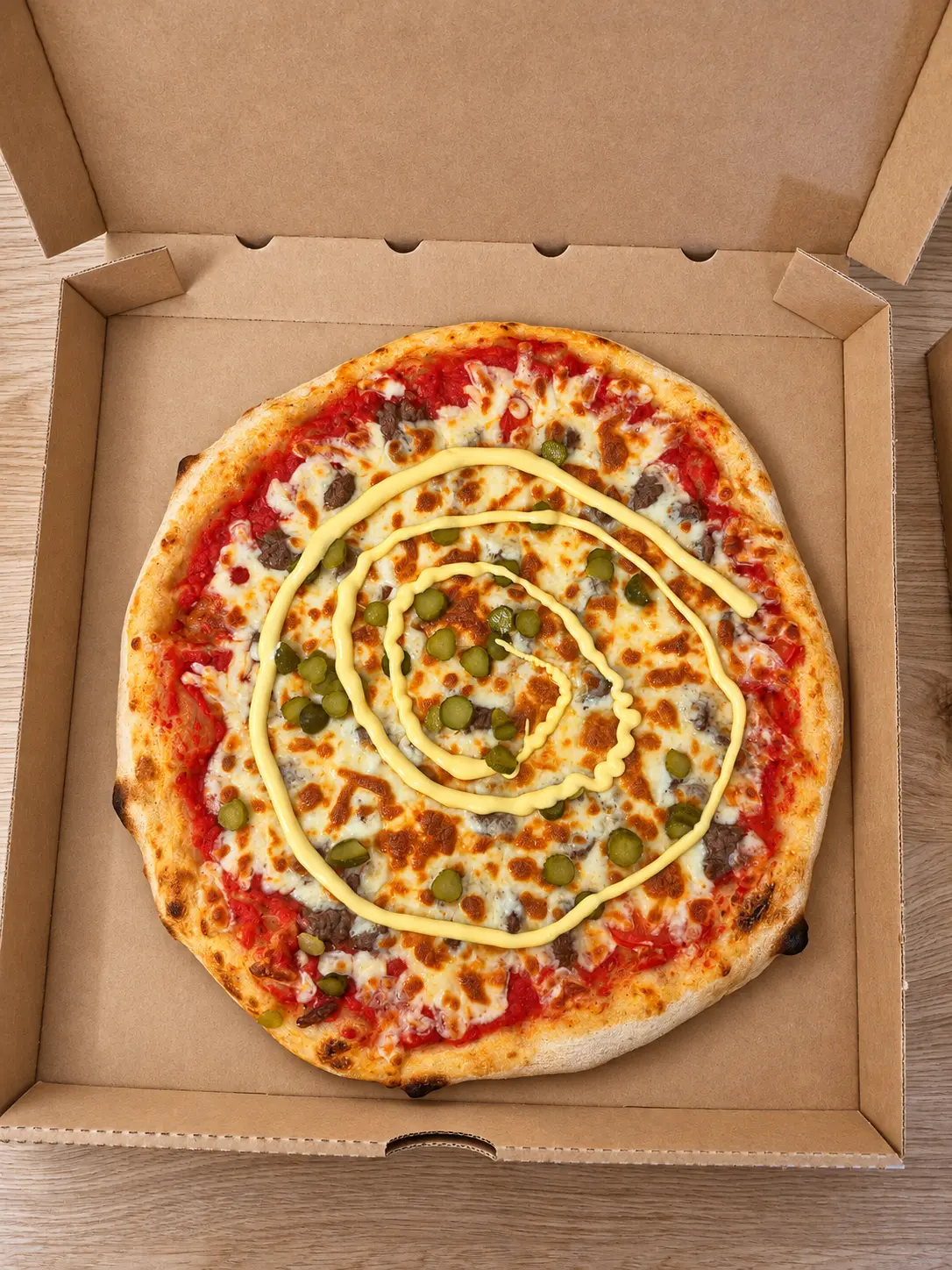 Pizza maison garnie de fromage, viande, cornichons et sauce