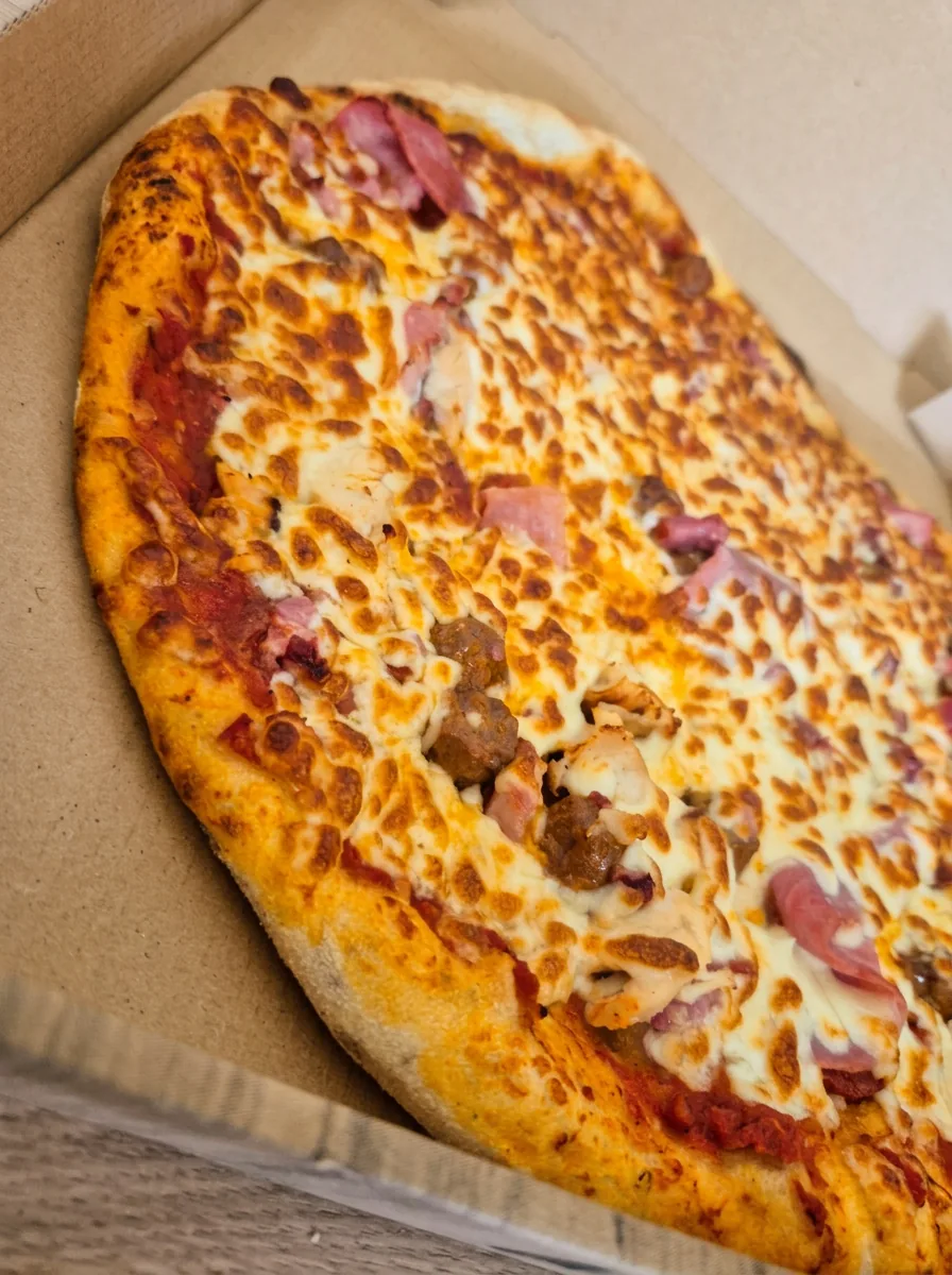 Pizza garnie de jambon, lardons et viande hachée